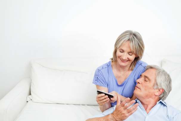Seniors shows elderly husband and wife looking at images on a mobile phone.
