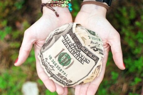 Socially responsible investing with hands holding ball of cash.