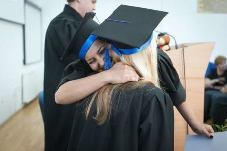 Recent College Grads With Two Graduate Women Hugging After Ceremony