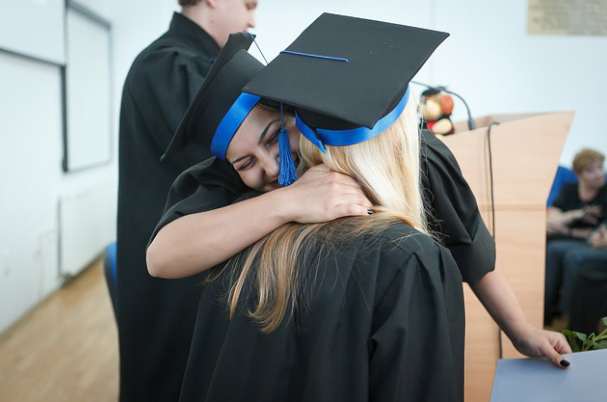 Recent College Grads With Two Graduate Women Hugging After Ceremony