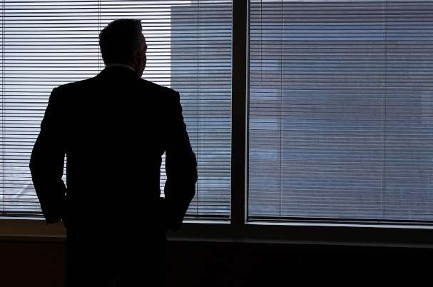 Business exit plan questions with man contemplatively looking out window.