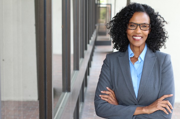 Case Study Chris Hodges on retiring early depicted by business woman standing with arms crossed in front of a office building hallway.