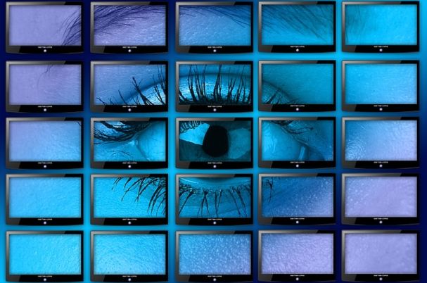 Credit Monitoring May Not Be Enough depicts woman's eye across 25 screens set in rows