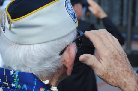 Guide to Federal Veterans Benefits with elderly man wearing military cap saluting.