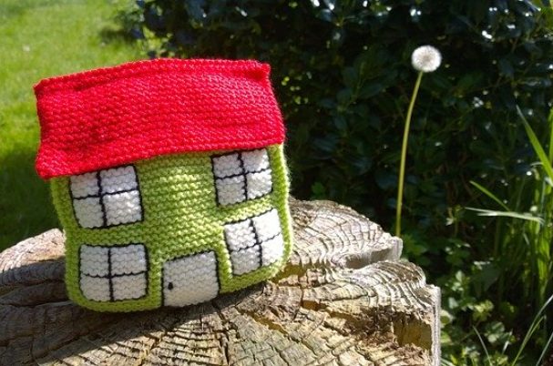 Reverse mortgage photo depicts a knitted house sitting on a tree stump.