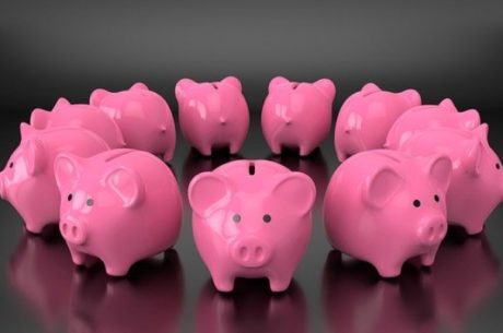 Roth IRAs Vs. Roth 401(k)s depicts circle of pink ceramic piggy banks.