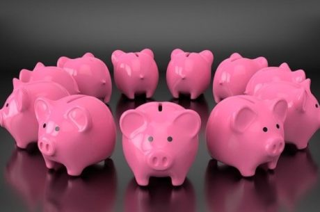 Roth IRAs Vs. Roth 401(k)s depicts circle of pink ceramic piggy banks.