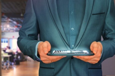 How the Expanded EIDL Program Can Help Your Small Business with businessman holding tablet that contains financial graphs.