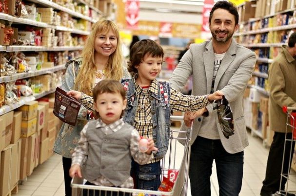 Tips for Teaching Your Children About Money With Man and Woman Grocery Shopping With Two Young Children.