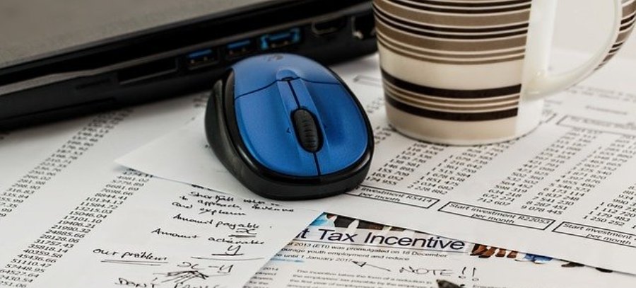 Tax Code image depicts tax account printouts with computer mouse and coffee mug sitting on top.