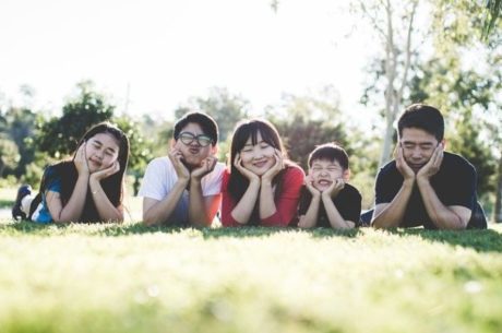 Should You Save for Retirement or for a Child’s College Education shows a family laying down with face in hands on grass.