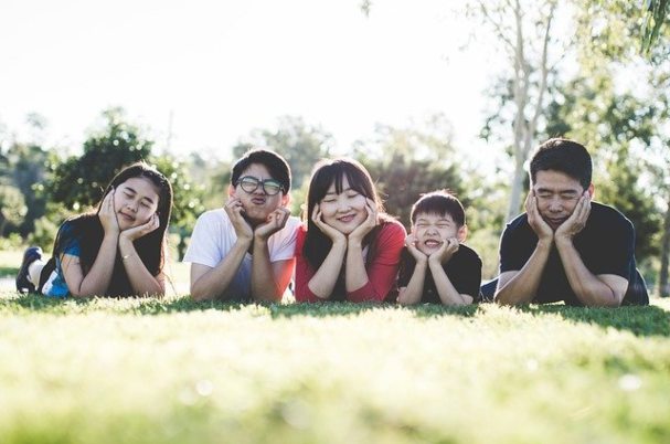Should You Save for Retirement or for a Child’s College Education shows a family laying down with face in hands on grass.