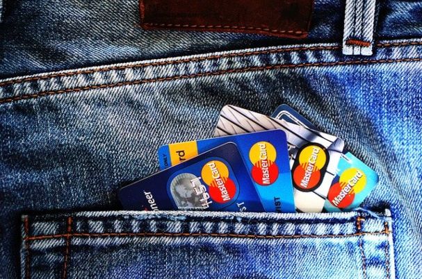 Managing Your Credit Score depicts multiple credit cards sticking out of jeans pocket.