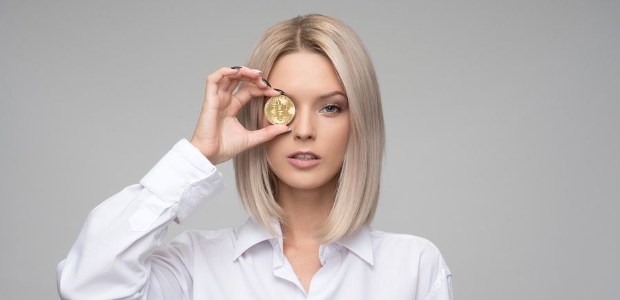 4 Things You Probably Didn’t Know About Cryptocurrencies Depicts Woman Holding Bitcoin Over her Eye.