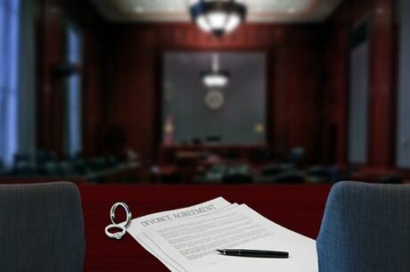 Dividing Retirement Assets at Divorce Depicts Divorce Agreement Document on Judge's Bench Overlooking Courtroom.