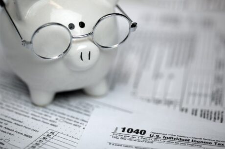 Your List of 12 Tax Reduction Strategies concept depicts US Tax forms with piggybank