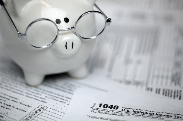 Your List of 12 Tax Reduction Strategies concept depicts US Tax forms with piggybank