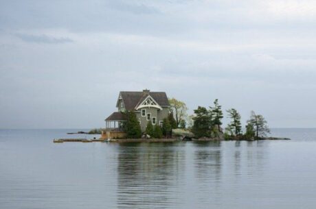 Vacation home is depicted with a small house surrounded by water on the middle of an island.