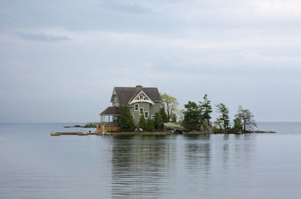 Vacation home is depicted with a small house surrounded by water on the middle of an island.