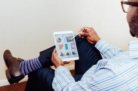 Deferring gains through 1031 exchanges shows man holding tablet with financial graphs on it.