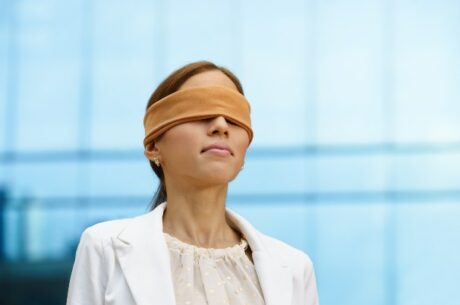 Using a blind trust to sell restricted stock depicts a blindfolded business woman.