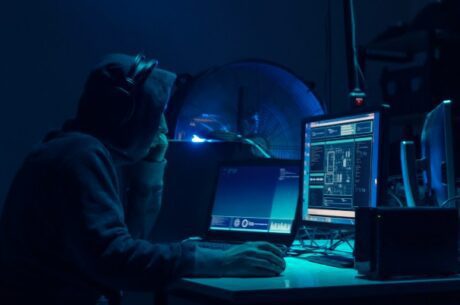 What Happens to Our Stolen Information After a Cyber Breach Image Shows Man in Hoodie Looking at a Computer.?