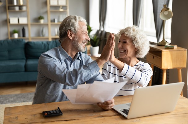 Employer-provided health insurance image of senior man and woman giving high-five.