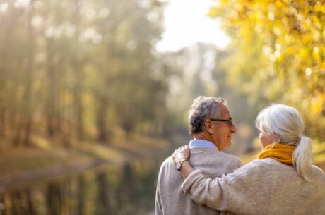The Transition into Retirement with elderly man and woman leisurely walking along river.