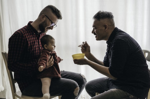 Estate Planning for LGBTQIA+ Married Couples with Two Married Men Feeding Their Baby.