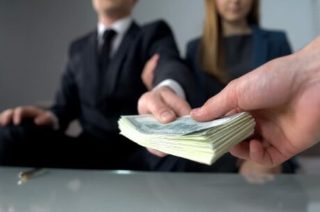 Determining the basis of inherited property shows a man and woman handing a stack of cash to another man.