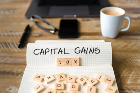 Introduction to Capital Gains Tax photo of paper, mug, and letter blocks.