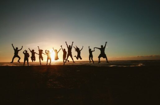 Guide to Charitable Giving photo of people on beach jumping up in front of sunset.