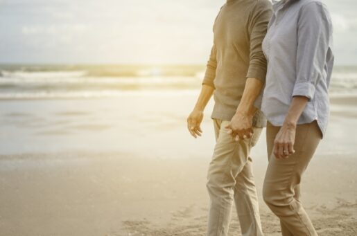 Retirement Planning photo of couple holding hands while walking on beach.