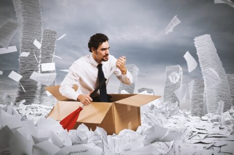 Common Tax Traps Involving Life Insurance photo of man in box, holding oar, in a sea of papers.