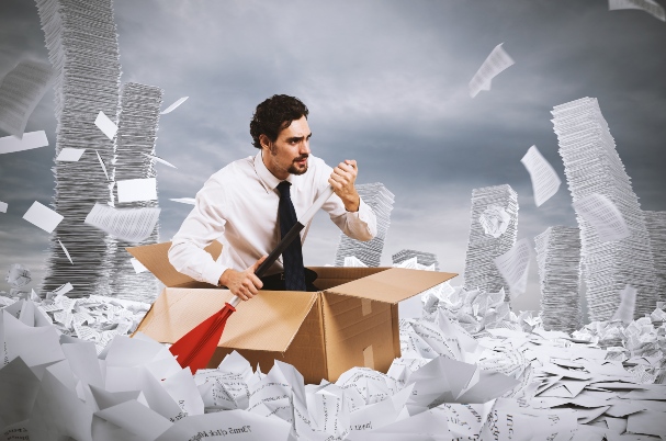 Common Tax Traps Involving Life Insurance photo of man in box, holding oar, in a sea of papers.