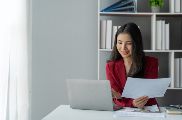 Tax Smart Planning Strategies concept with smiling Asian businesswoman working on tax documents within the office.