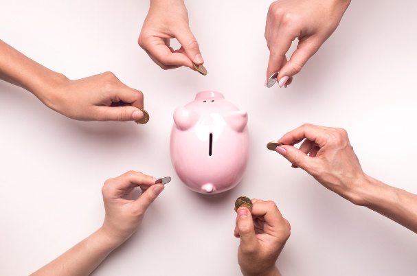 Multiple people putting coins in a piggybank inCrowdfunding