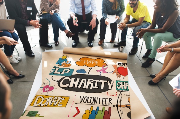 Charitable gift annuities (CGAs) shows People Sitting Around a Poster on the Floor that Talks about Charity, Hope, and Giving.