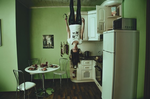 Decoding the Debt Ceiling Crisis concept depicts upside down woman standing on ceiling.