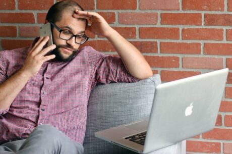 A market outlook for the coming year concept with frustrated man on phone while looking at computer.