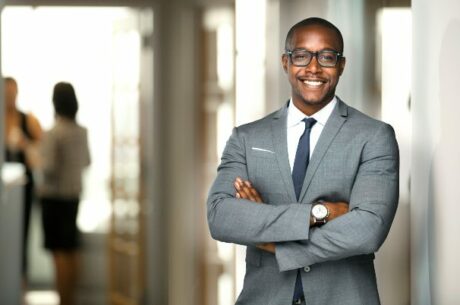 Executive's Guide to Retirement photo concept with confident businessman crossing his arms while standing in front of an office entrance.