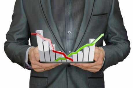 Roth 401(k) and 403(b) Plans concept with businessman holding tablet with financial graphs rising above it.