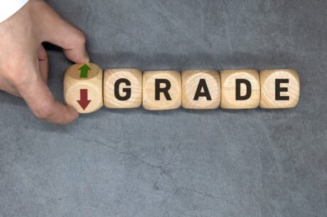 Downgrade depicted by man flipping wood spelling blocks with an up and down arrow in front of the word grade.