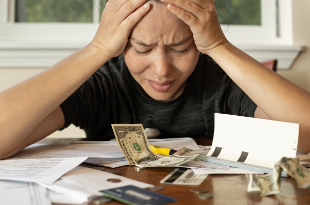 Financially prepared for an emergency is depicted by a frustrated sad woman worrying about paying her financial bills at home. Money crisis.