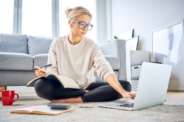 Women breadwinners image is depicted by a young woman sitting cross-legged on the floor and typing into a laptop computer.