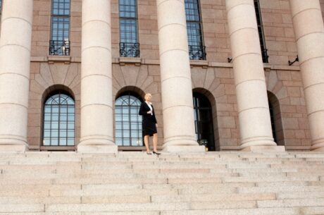 7 Pillars of Financial Success depicts Businesswoman standing by building, wide angle view